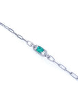 A white gold paperclip bracelet with a colombian emerald on a top far view.