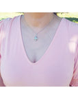 Pear-shaped Welo Ethiopian opal pendant in sterling silver with cubic zirconia, worn on a pink top.