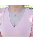 Pear-shaped Welo Ethiopian opal pendant in sterling silver with cubic zirconia, worn on a pink top.