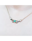 14K yellow gold Claddagh necklace with a heart-cut emerald, worn on a chest.