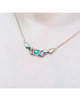 14K yellow gold Claddagh necklace with a heart-cut emerald, worn on a chest.