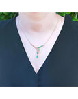 14K yellow gold necklace with marquise and pear-shaped Colombian emeralds and diamonds on a woman's neck.
