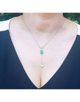 14K white gold necklace with emerald cushion cut pendant, dangling diamond cluster, and white freshwater pearl.