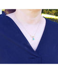 18K yellow gold bow-tie emerald necklace with a dangling pear-shaped emerald and yellow diamond accents.