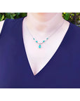 14k white gold necklace with pear-shaped emeralds and diamonds on a model.