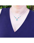 14k white gold necklace with pear-shaped emeralds and diamonds on a model.