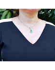Woman wearing an 18K gold emerald and diamond enhancer necklace with a pear-shaped green emerald.