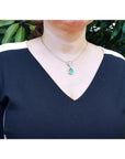 Woman wearing an 18K gold emerald and diamond enhancer necklace with a pear-shaped green emerald.