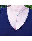 Emerald lariat necklace with an emerald-cut natural emerald, milgrain, prongs, and dangling pearls on a gold box chain.