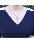 Marquise cut Colombian emerald necklace with diamond links in 14K white gold on a woman's chest.