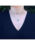 Woman wearing 18K yellow gold necklace with a vibrant deep green emerald solitaire pendant.