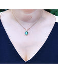 Women's emerald and diamond necklace emerald-cut natural emerald deep green bluish color, encircled by a halo diamond