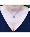 Women's emerald and diamond necklace emerald-cut natural emerald deep green bluish color, encircled by a halo diamond