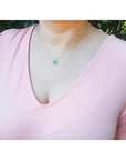 1.31 ct emerald-cut Muzo Colombian emerald necklace with diamonds in 14K yellow gold on a model.