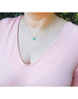 1.31 ct emerald-cut Muzo Colombian emerald necklace with diamonds in 14K yellow gold on a model.