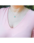 1.31 ct emerald-cut Muzo Colombian emerald necklace with diamonds in 14K yellow gold on a model.