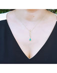 14K yellow gold twisted slider necklace with a pear-shaped Colombian emerald pendant on a woman's neck.