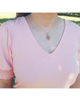 Ethiopian opal pendant with vibrant play of colors and brown pinpoint fire, wire-wrapped in silver, worn on a pink blouse.