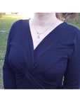 14K white gold necklace with a pear-shaped emerald and diamond chevron pendant on a woman.