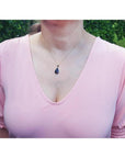 Wello black opal pendant necklace with red-orange fire and blue-green flashes on a 14K yellow gold chain.