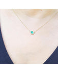 Vibrant pear-shaped emerald necklace with diamond halo on a delicate 14K yellow gold chain.