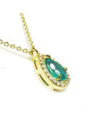 Pear-shaped natural emerald necklace with diamond halo in 14K yellow gold.