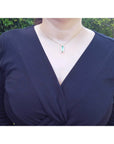 Emerald baguette cut necklace with natural diamonds, 14K yellow gold, worn on a black top.