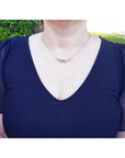 Woman wearing a blue top with puffed sleeves and a Claddagh emerald heart necklace outdoors.