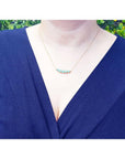 14K gold necklace with five round, medium light green Colombian emeralds of varying sizes.