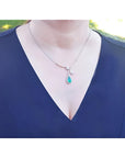 Pear cut 2.26 carat natural emerald necklace in 18K white gold with diamond halo on a woman.