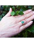 Women's 14K yellow gold ring with a rectangular emerald and three accent diamonds on each side.