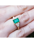 Women's 14K yellow gold ring with a rectangular emerald-cut deep bluish-green emerald and diamond accents.