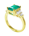 An emerald and accent side diamond ring side view.