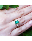Women's 14K yellow gold ring with a rectangular emerald and three accent diamonds on each side.