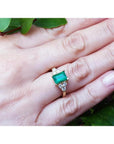 Women's 14K yellow gold ring with a rectangular emerald and three accent diamonds on each side.
