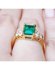 Women's 14K yellow gold ring with a rectangular emerald-cut deep bluish-green emerald and six accent diamonds.