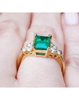 Women's 14K yellow gold ring with a rectangular emerald-cut deep bluish-green emerald and six accent diamonds.