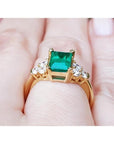 Women's 14K yellow gold ring with a rectangular emerald-cut deep bluish-green emerald and six accent diamonds.