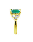 14K yellow gold ring with a rectangular emerald and three accent diamonds on each side.