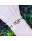 Emerald oval cut bracelet in 14K yellow gold with diamonds, worn on a wrist.