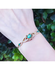 Emerald oval cut bracelet in 14K yellow gold with diamonds, worn on a wrist.