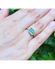 1.30 carat emerald-cut natural Colombian emerald ring in 14K yellow gold, east-west style, on a hand.