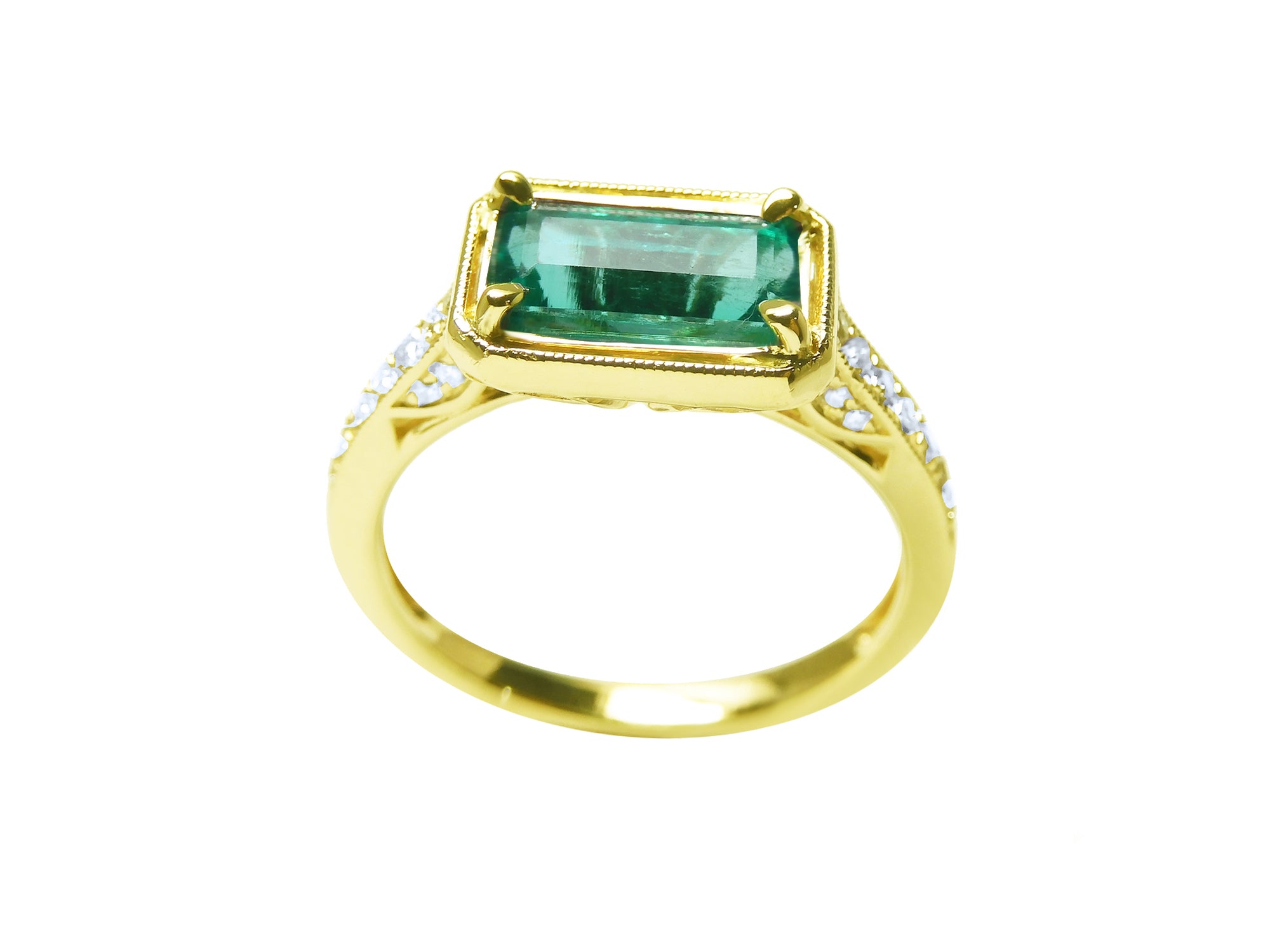 Gold ring with a natural emerald and diamond accents on a white background