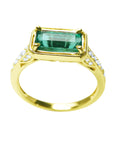 Gold ring with a natural emerald and diamond accents on a white background