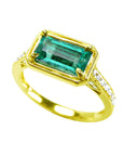 The tilted position of this natural emerald ring showcases the top centered gemstone and sides perspectives.