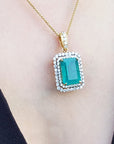 Gold necklace with a natural emerald pendant on a person wearing a black outfit.