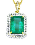 The topside of a pendant with a rectangular emerald encircled by a double halo diamond in yellow gold.