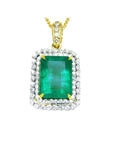The topside of a pendant with a rectangular emerald encircled by a double halo diamond in yellow gold.