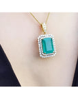 Gold necklace with a natural emerald into a double halo diamond pendant on a person's neck.