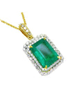 A yellow gold emerald pendant displaying the topside rectangular emerald surrounded by a double halo diamond.